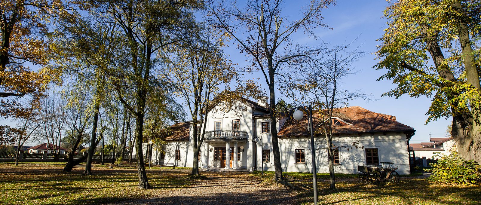 Dwór wśród jesiennych drzew parku, aleja prowadząca do ganku